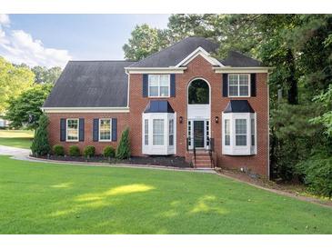 Charming two-story brick home with manicured lawn and dark shutters at 1001 Braelin Ct, Woodstock, GA 30189