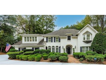 Beautiful two-story home with white painted brick, manicured landscaping and an American flag at 8480 Valemont Dr, Sandy Springs, GA 30350