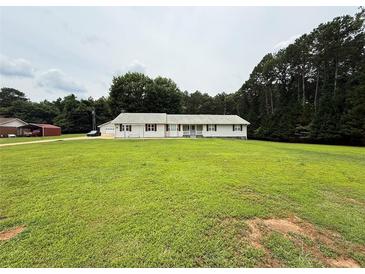 Inviting ranch-style home boasts a sprawling lawn, complemented by mature trees and a quaint, covered front porch at 95 Oak Grove Cir, Mcdonough, GA 30253