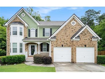 Charming two-story home boasts brick and green siding, plus an attached two-car garage and inviting front porch at 157 Spur Ln, Hiram, GA 30141
