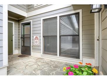 Cozy patio area featuring stone flooring, gray siding, flowers and a screened door at 4977 Meadow Ln, Marietta, GA 30068