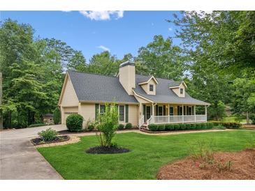 Charming home featuring a welcoming front porch, lush landscaping, and attached garage at 1420 Pilgrim Rd, Cumming, GA 30040