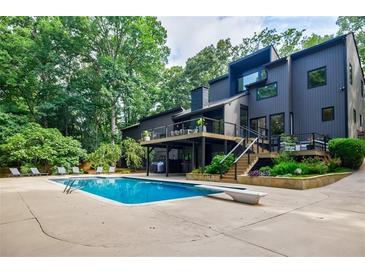Stunning backyard featuring a large inground pool, diving board, sun loungers, and multilevel deck overlooking lush greenery at 1510 Chevron Dr, Sandy Springs, GA 30350