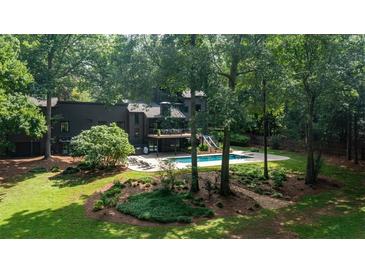 Spacious backyard featuring a modern home, a well-maintained pool, and ample greenery and mature trees at 1510 Chevron Dr, Sandy Springs, GA 30350