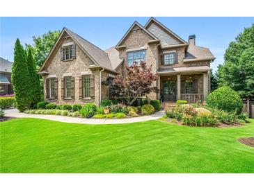 Beautiful brick home featuring manicured landscaping, lush green lawn and charming covered front porch at 2953 Kings Walk Ave, Marietta, GA 30062