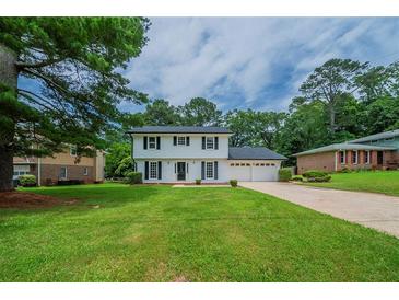 Charming two-story home featuring classic black shutters, lush green lawn and an attached two car garage at 4732 Manly Ct, Stone Mountain, GA 30088