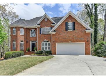 Charming two-story red brick home with a well-manicured lawn and attached two car garage at 525 Water Shadow Ln, Alpharetta, GA 30022