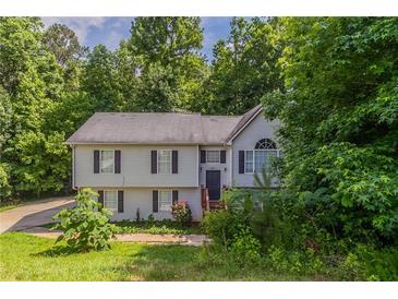 Traditional two-story home featuring neutral siding, black shutters, and mature trees in a serene, wooded setting at 1404 Lancaster Ct, Mcdonough, GA 30252