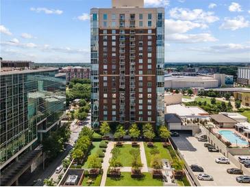 A high-rise building overlooks manicured grounds, a parking deck, and an outdoor pool on a sunny day at 285 Centennial Olympic Park Nw Dr # 809, Atlanta, GA 30313