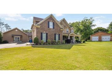 Two-story brick home features a well-manicured lawn, charming front porch, and a separate two-car garage at 739 E Mays E Rd, Stockbridge, GA 30281