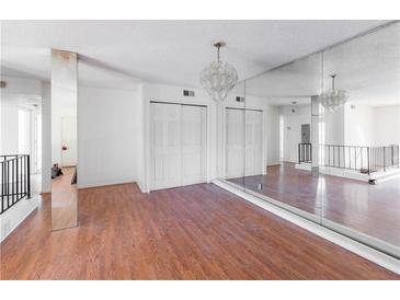 Spacious living room featuring wood floors, a mirrored wall, and an elegant chandelier at 1213 Camelot Dr, Atlanta, GA 30349