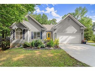 Charming home featuring a gray exterior, well-manicured lawn and landscaping, attached garage, and a bright yellow front door at 2730 Samples Rd, Cumming, GA 30041