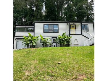 Charming two-story home boasts lush landscaping and a welcoming yellow front door at 2170 Beecher Sw Cir, Atlanta, GA 30311
