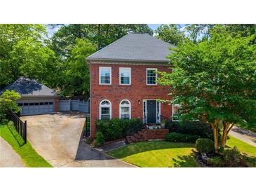 Charming brick two-story home with lush landscaping, a detached garage, and a welcoming front entrance at 2870 Livsey Woods Dr, Tucker, GA 30084