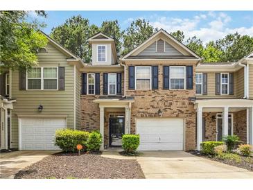 Two-story brick and vinyl townhome with a one-car garage, black shutters, and manicured landscaping at 3335 Thornbridge Dr, Powder Springs, GA 30127