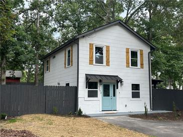 Charming two-story home with white siding, wood shutters, gray fence and inviting light blue front door at 5090 Lorraine Pl, Forest Park, GA 30297