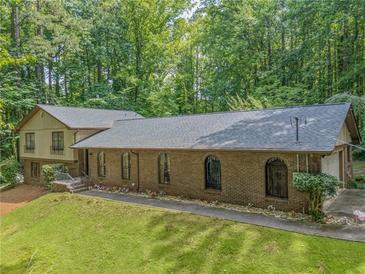 Charming brick home with arched windows, lush lawn, and surrounded by mature trees at 5632 Stillwater Ct, Stone Mountain, GA 30087