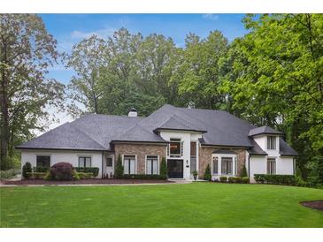 Stunning stone and white two-story home with meticulously maintained lawn and lush landscaping at 1460 Lakemist Ct, Roswell, GA 30075