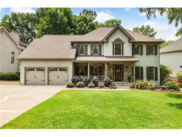 Charming two-story home features a well-manicured lawn, stone accents, and a welcoming front porch perfect for relaxing at 10530 Tuxford Dr, Alpharetta, GA 30022