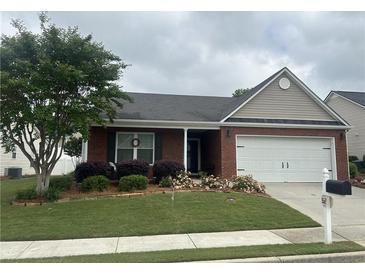 Charming single-story brick home featuring a well-manicured lawn, a two-car garage, and lovely front yard landscaping at 804 Village Pl, Loganville, GA 30052