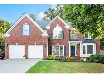Charming two-story brick home featuring a well-manicured lawn and attached two-car garage at 5204 Tealing Ne Dr, Roswell, GA 30075