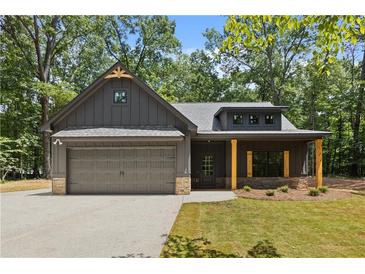 Charming home with neutral siding, a two-car garage, and inviting front porch with rustic columns at 1687 Harmony Rd, Temple, GA 30179
