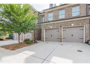 Brick townhome showcasing a two-car garage and concrete driveway at 5535 Bright Cross Way, Suwanee, GA 30024