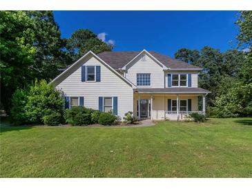 Charming two-story home featuring a manicured lawn, inviting porch, and classic architectural details at 1615 Burnt Oak Way, Dacula, GA 30019