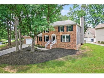 Charming two-story brick home with mature trees, a manicured lawn, and a classic architectural style at 4619 Villa Chase Ne Dr, Marietta, GA 30068
