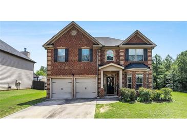 Charming two-story brick home featuring a two-car garage, well-manicured lawn, and classic architectural details at 10044 Cormac St, Jonesboro, GA 30238
