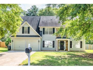 Charming two-story home featuring an attached two-car garage, lush landscaping, and inviting front porch at 40 Queensland Ln, Covington, GA 30016