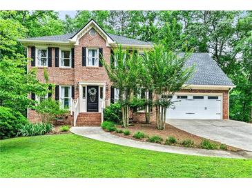 Charming two-story brick home with a well-manicured lawn and mature landscaping at 135 Crimson Rdg, Tyrone, GA 30290