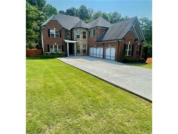 Charming two-story brick home with a well-manicured lawn and a spacious driveway leading to a three-car garage at 3499 Lake Mill Rd, Buford, GA 30519