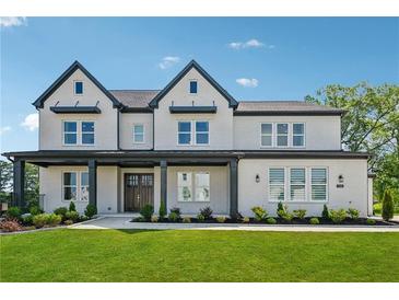 Beautiful two-story home features a well-manicured lawn, inviting front porch, and classic design elements at 7420 Wild Violet Dr, Cumming, GA 30040