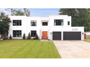 Stunning modern home featuring an attached two-car garage, manicured lawn and eye-catching orange front door at 2220 Meadowvale Ne Dr, Atlanta, GA 30345