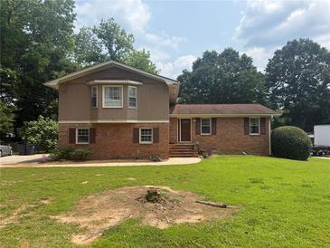 Charming two-story home featuring brick and wood facade with a well-maintained lawn and mature trees at 2206 Rhett Ct, Lawrenceville, GA 30044