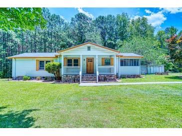 Charming single-story home with a well-maintained lawn, inviting front porch, and beautiful surrounding trees at 5160 W Chapel Hill Rd, Douglasville, GA 30135