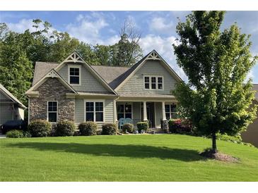 Charming home featuring a stone facade, covered porch, manicured lawn, and mature landscaping at 37 Grand Georgian Ne Ct, Cartersville, GA 30121