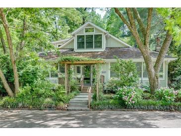 Charming home featuring a lush, landscaped front yard and inviting entrance with pergola at 4621 Lakeshore Dr, Pine Lake, GA 30072