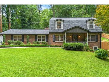 Charming brick home with a well-manicured lawn and lush greenery, showcasing classic architectural details at 1050 Lake Charles Dr, Roswell, GA 30075