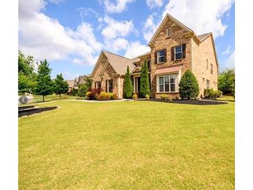 Lovely brick home featuring manicured lawn, beautiful landscaping, and shuttered windows at 6110 Read Rd, Suwanee, GA 30024
