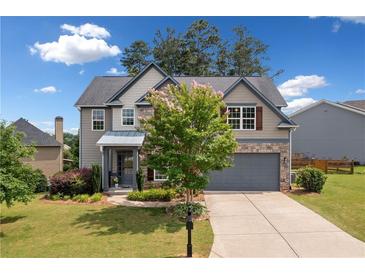Charming two-story home with stone accents, gray siding, well-manicured lawn and a two car garage at 115 Greenbrier Way, Canton, GA 30114