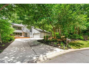 Inviting home featuring a large front yard, driveway, two-car garage, and a charming deck area perfect for enjoying the outdoors at 4290 Inverness Ne Ct, Roswell, GA 30075