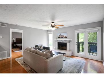 Bright living room with a fireplace, ceiling fan, and access to a balcony with a seating area at 903 Tuxworth Cir, Decatur, GA 30033