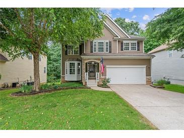 Charming two-story home featuring a well-manicured lawn, a two-car garage, and beautiful landscaping at 950 Mill Creek Ave, Canton, GA 30115