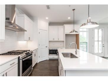Modern kitchen features white cabinets, stainless steel appliances, and a large island with quartz countertop at 348 Olmstead Way # 30, Alpharetta, GA 30022