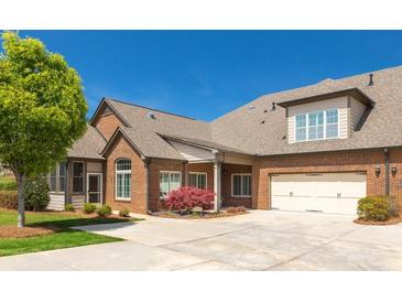 Lovely brick home featuring an attached two-car garage, manicured lawn, and mature trees on a sunny day at 328 Brookhaven Walk, Johns Creek, GA 30097