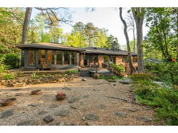 Expansive backyard with mature landscaping, a brick home and a deck that overlooks lush greenery at 1850 Winchester Trl, Brookhaven, GA 30341