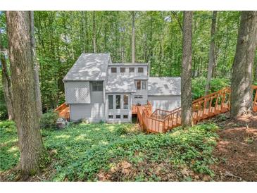 View of the exterior of a multi-story home nestled in a wooded lot with a wooden deck and stairs at 1279 Colony Pl, Marietta, GA 30068