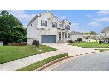 Charming two-story home with a painted brick facade, blue garage door, manicured lawn and inviting entryway at 610 Brickstone Ct, Covington, GA 30016